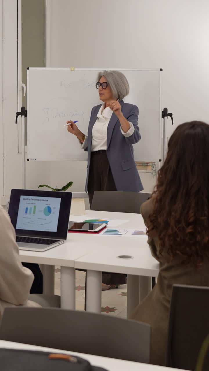 Insegnante matura che spiega e presenta argomenti agli studenti in un'aula moderna