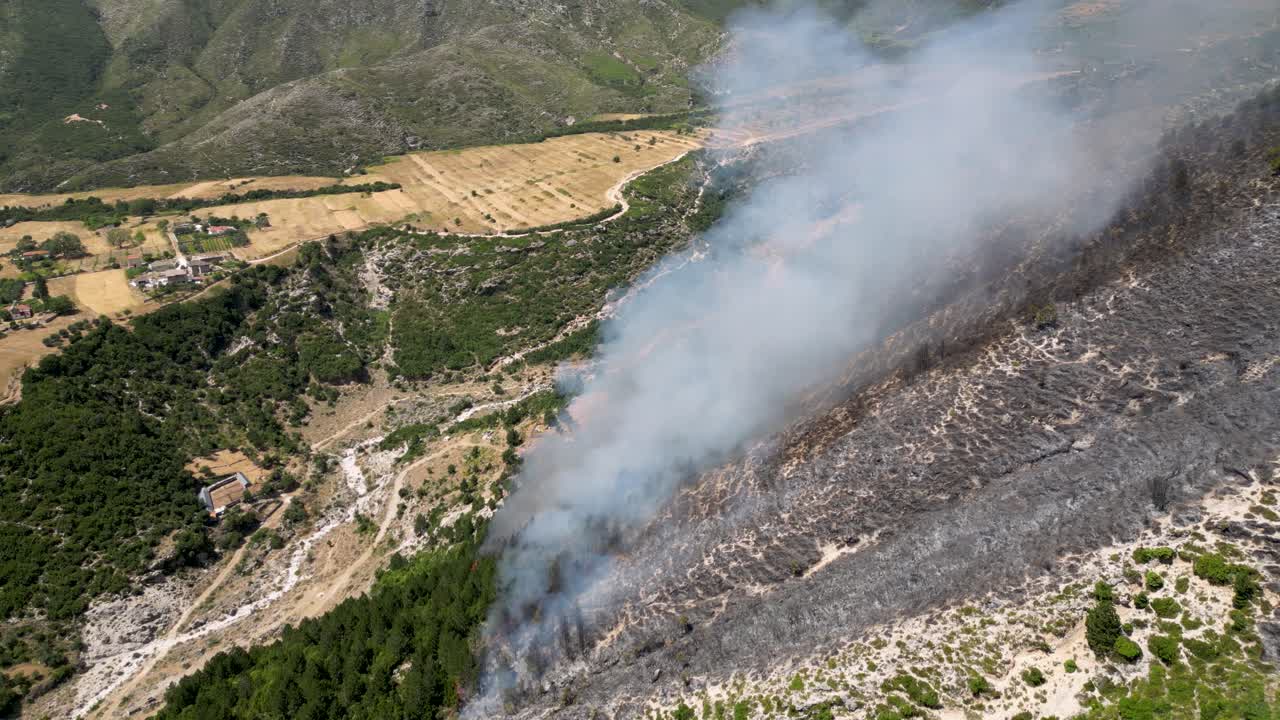 Smoke on the mountain coming from burning forest and trees heading towards the valley