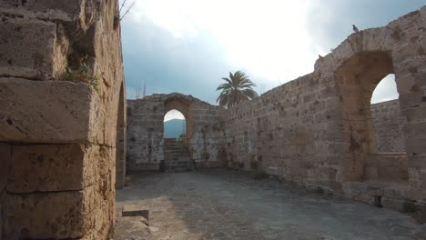 Ruins-of-Kyrenia-Castle-ramparts-and-old-archways-during-gold-evening-in-Cyprus---Wide-gimbal-shot