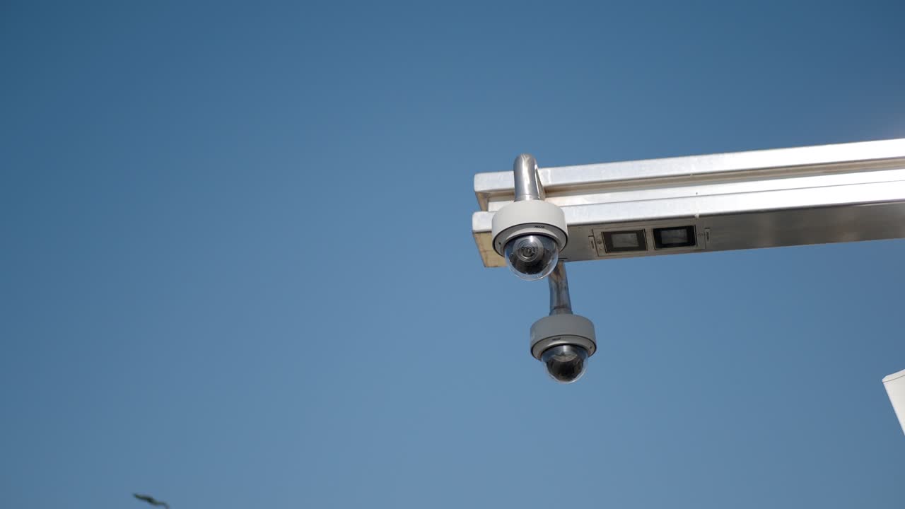 dos cámaras de seguridad montadas en un poste contra un cielo azul