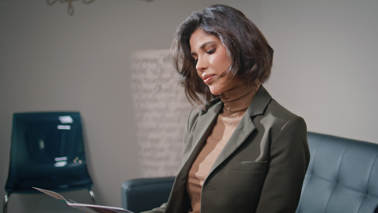 Corporate visitor sitting sofa looking at magazine closeup. Confident woman