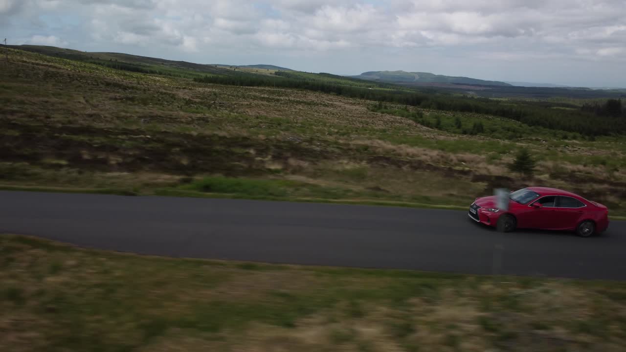 vehículo rojo que viaja a lo largo de una carretera de vía única en el país, aérea