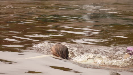 little girl swimming in a muddy lake in slow motion