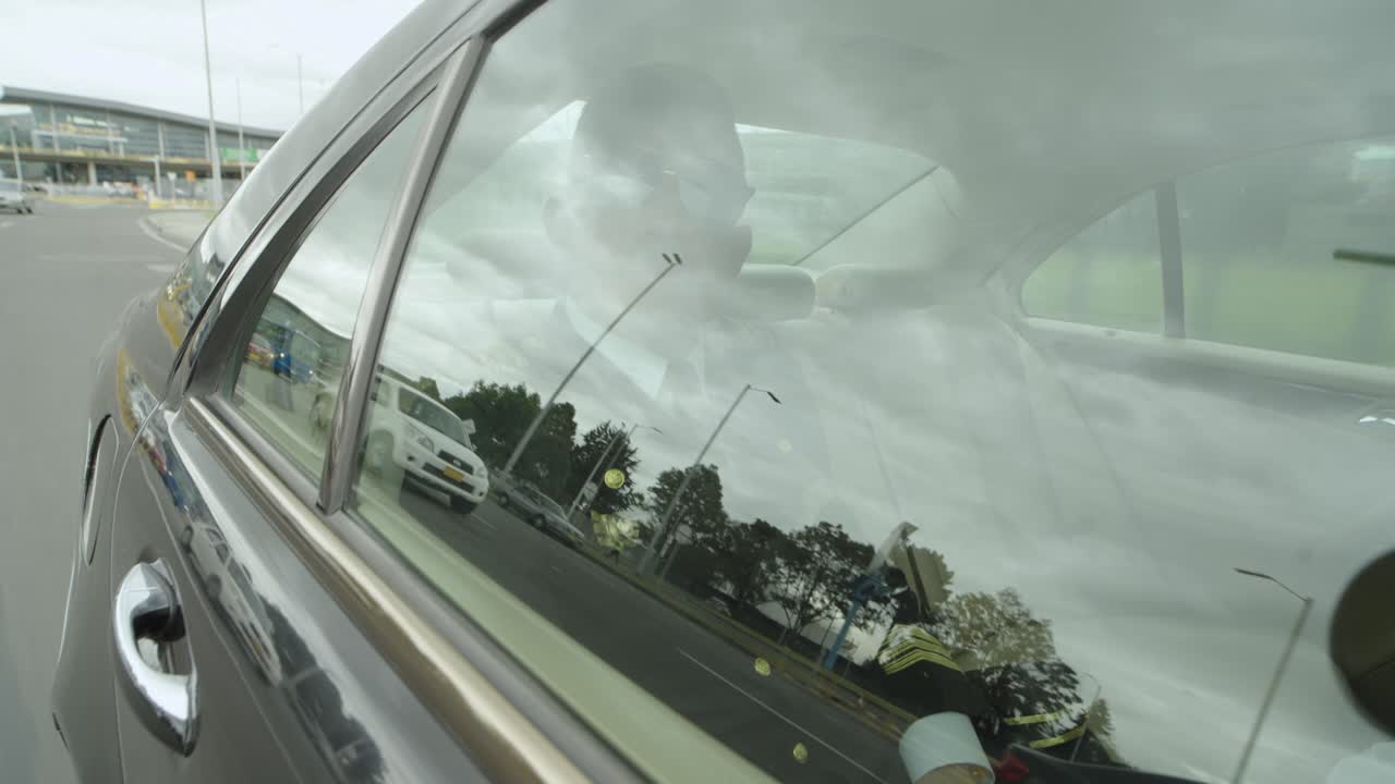 A pilot sits in a black car that drives him to airport