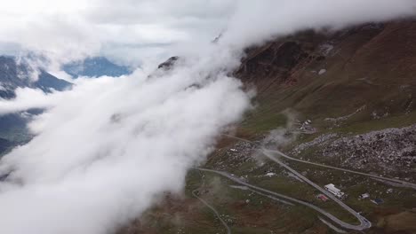 nubes que se mueven sobre un paisaje montañoso rocoso atravesado por carreteras sinuosas y colinas nevadas en el fondo