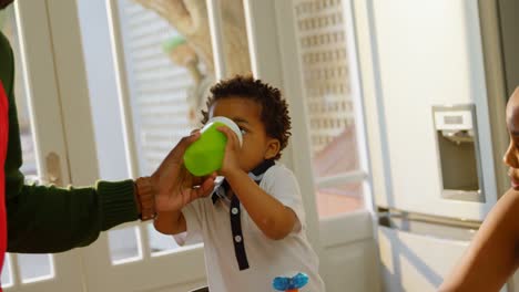 mid section of black father feeding water to his son in kitchen of comfortable home 4k