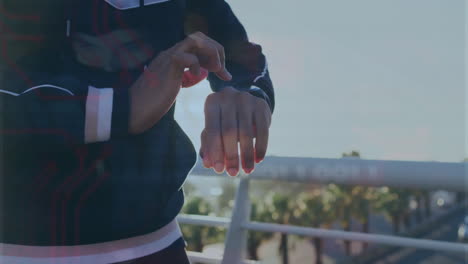 checking smartwatch, person standing on bridge with palm trees in background