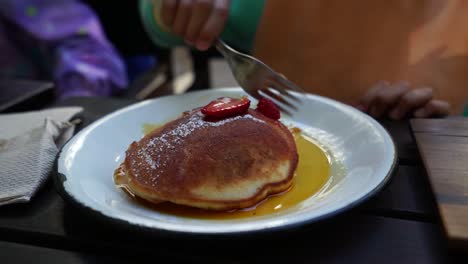 kid eating breakfast, plate of medium size pancakes, honey and strawberry topping