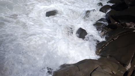 white foam on black carved cliffs, rocky shore, and sea waves splashing in spectacular foam - a natural wonder coastal marvel