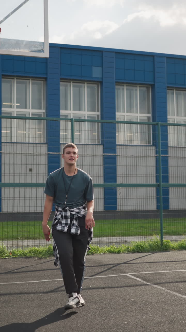 el deportista lanza la pelota de voleibol, salta y la golpea mientras está de pie en la cancha de baloncesto, el edificio azul y el fondo cercado hacen un tiro dinámico y enérgico lleno de acción y movimiento deportivo