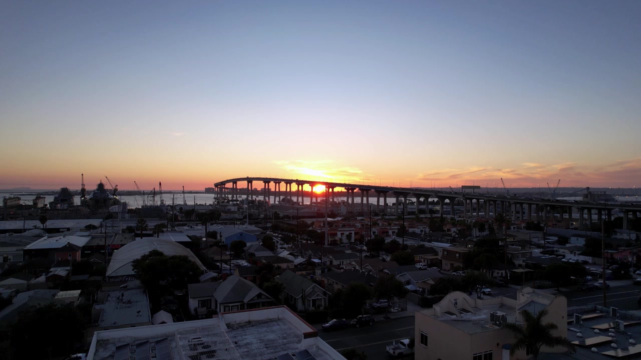 Dron lecący w kierunku samochodów jadących po moście Coronado o zachodzie słońca w San Diego w Kalifornii, uchwycający ruch uliczny i atmosferę panoramy miasta.
