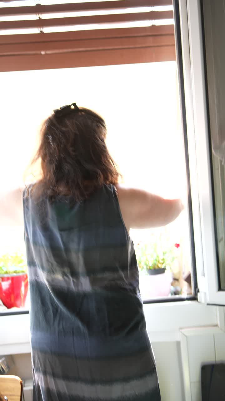 Woman at a window in a kitchen, preparing food
