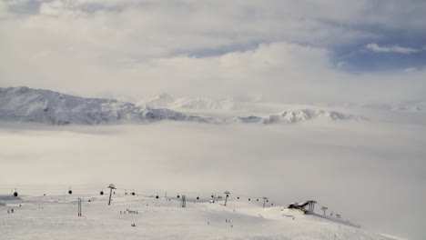 time lapse of skiers and ski lifts in meribel in the french alps with mountains and moving cloud in the background