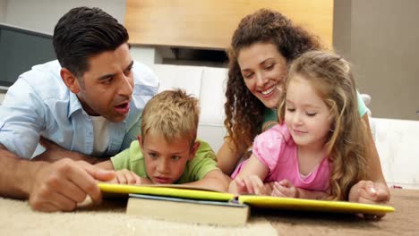 hermanos acostados en el suelo leyendo un libro con los padres