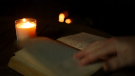 un hombre leyendo un libro antiguo junto a un fuego acogedor e iluminado a la luz de las velas