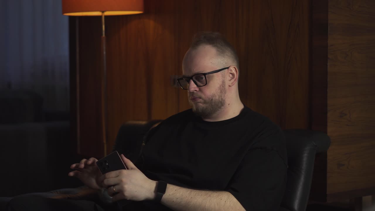 Frustrated man sitting indoors ignores or declines a phone call, showing annoyance, conflict, and communication breakdown
