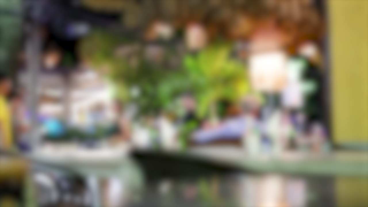 A vibrant, blurred street scene in Thailand with people and greenery, captured in dynamic motion