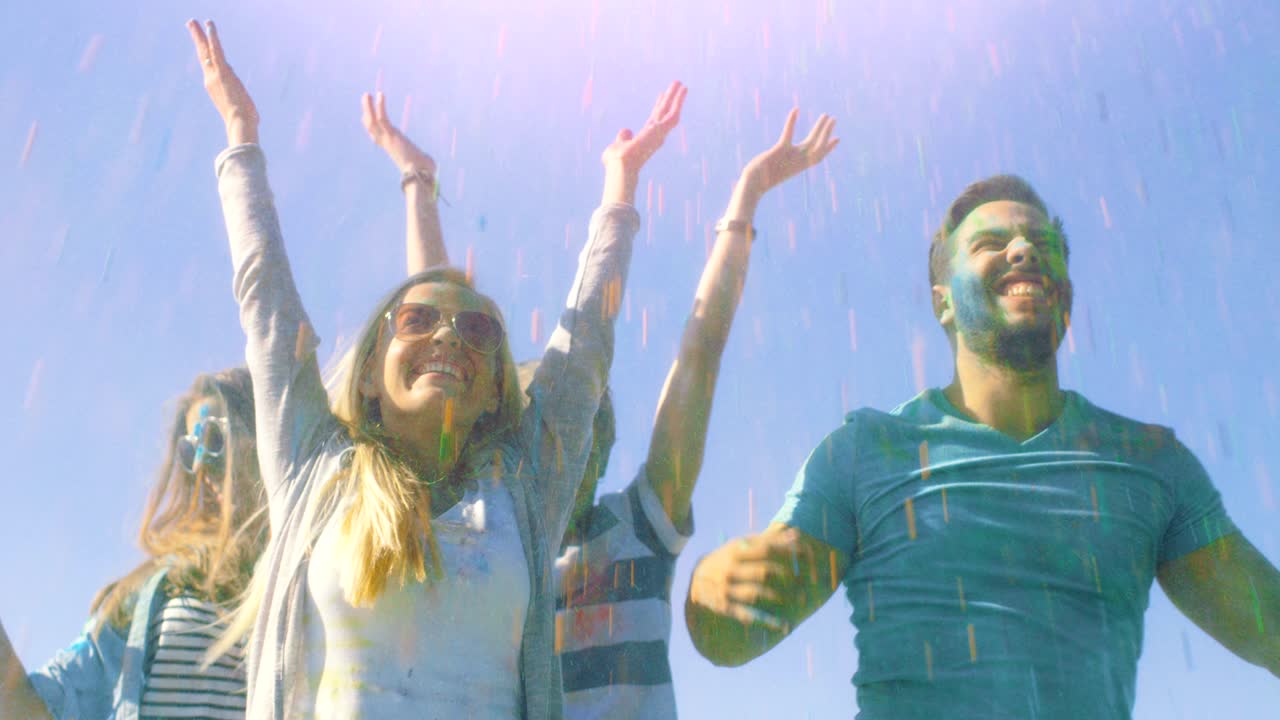 un grupo multiétnico de jóvenes diversos salta y lanza polvo de colores en el aire en la celebración del festival de holi. se divierten enormemente en este día soleado.