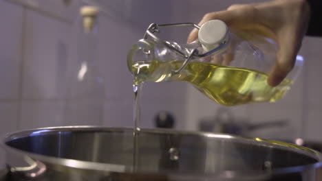 slowmotion close shot as a hand pouring olive, or sunflower oil in a pot from a bottle