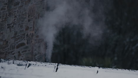 Steam-or-smoke-coming-from-small-chimney-on-roof-on-winter's-day