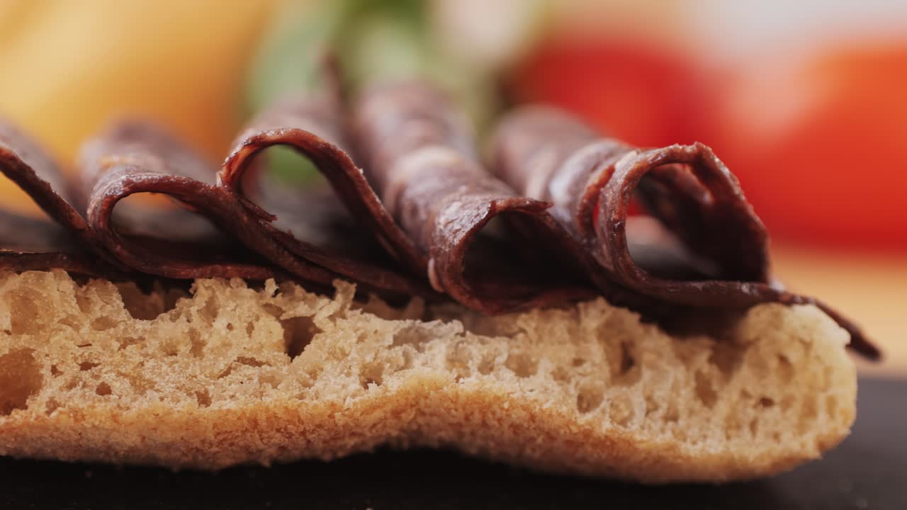 black bull sausage ham, tongue pork dry-cured sausage on a black background, traditional spanish delicatessen food, close up.