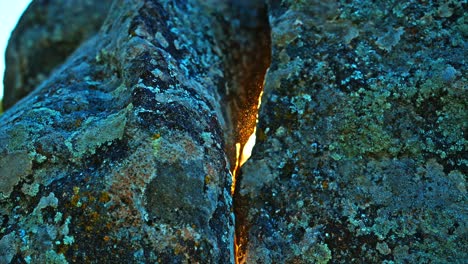 a close-up view of two ancient stone surfaces, with a small gap where sunlight gently filters through, revealing fine dust particles illuminated in the light