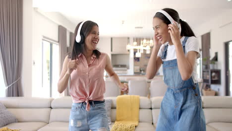 listening to music with headphones, two teenage girls laughing and dancing