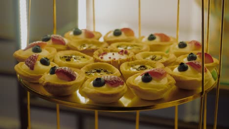 Close-up-shot-with-a-gold-cake-stand-filled-with-multiple-cupcakes,-tracking-shot