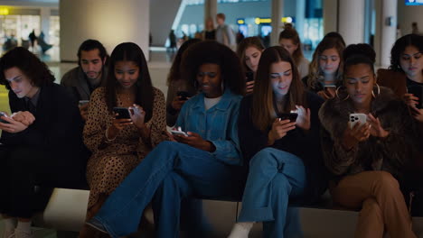 diverse group of people engrossed in smartphones in a public space