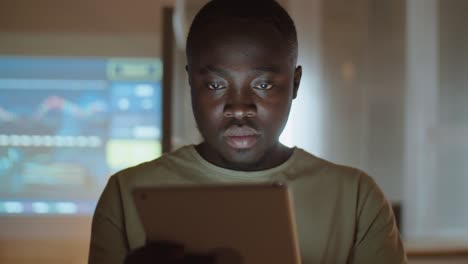 african american man working on tablet in office at night
