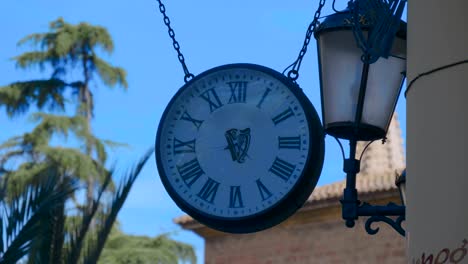 round white clock on the street on the wall of the house against the blue sky