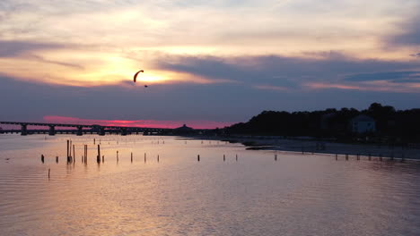 parallax drone shot of paramotor flying during golden hour near beach in mississippi