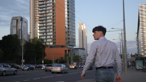 young businessman walking in the city center, traffic, bus, buildings in background