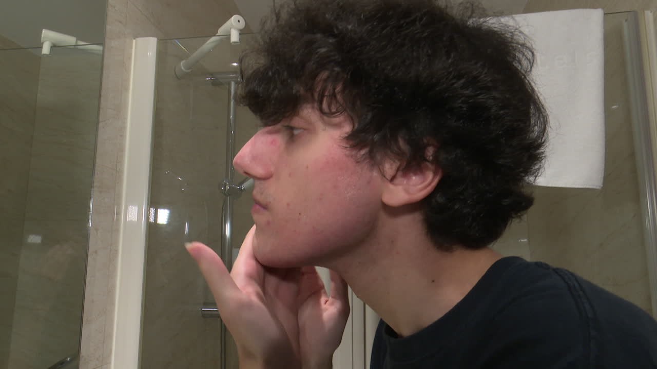 Young Man Washing His Face in a Hotel Bathroom