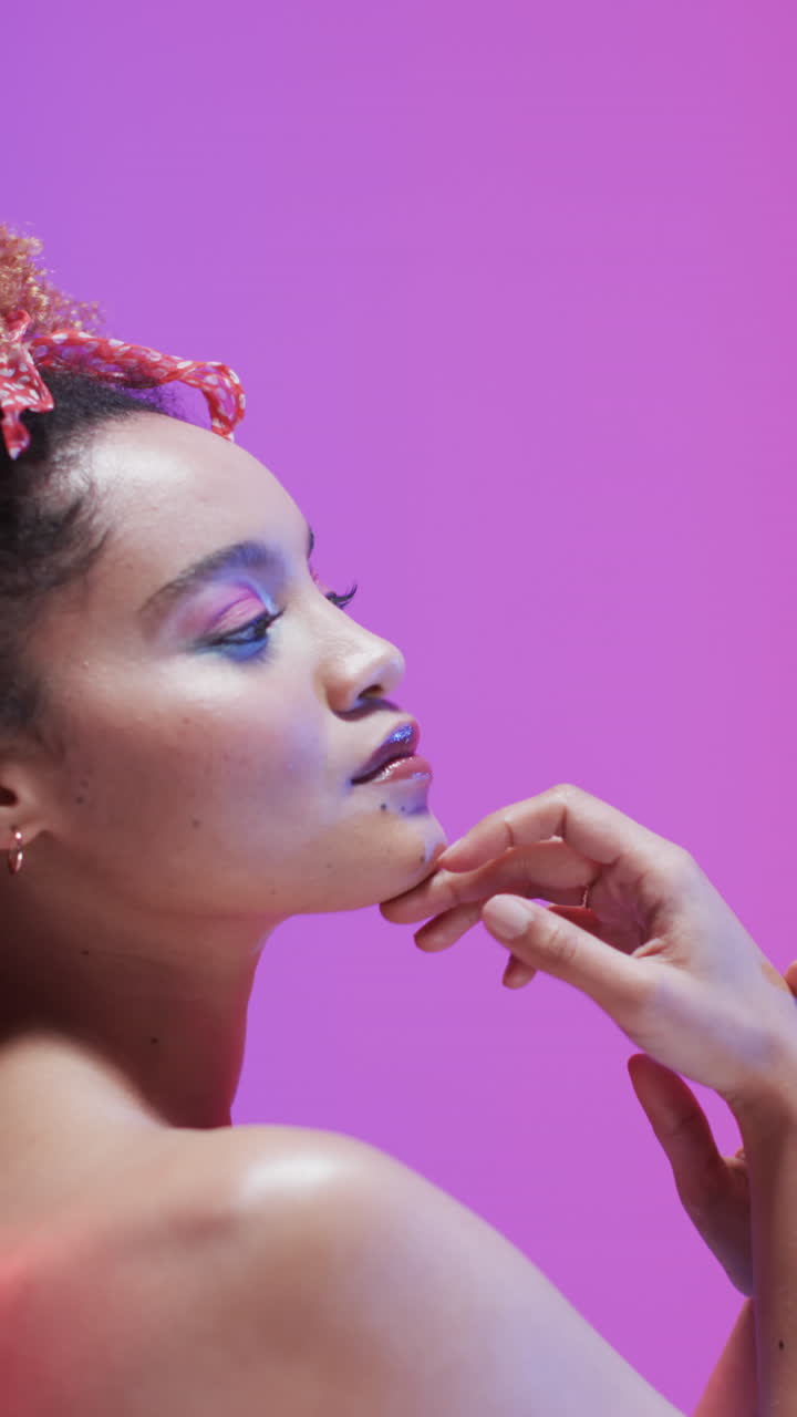 Vertical video of biracial woman with dark hair in blue and pink light, slow motion