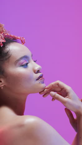 vertical video of biracial woman with dark hair in blue and pink light, slow motion