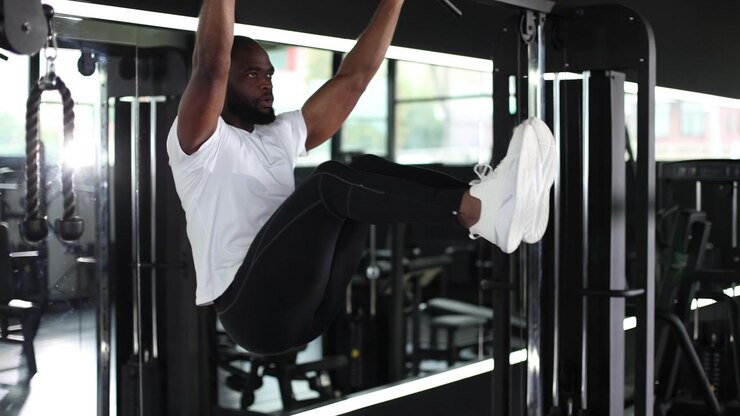 Fit African American Man Doing Hanging Leg Raises in Modern Gym