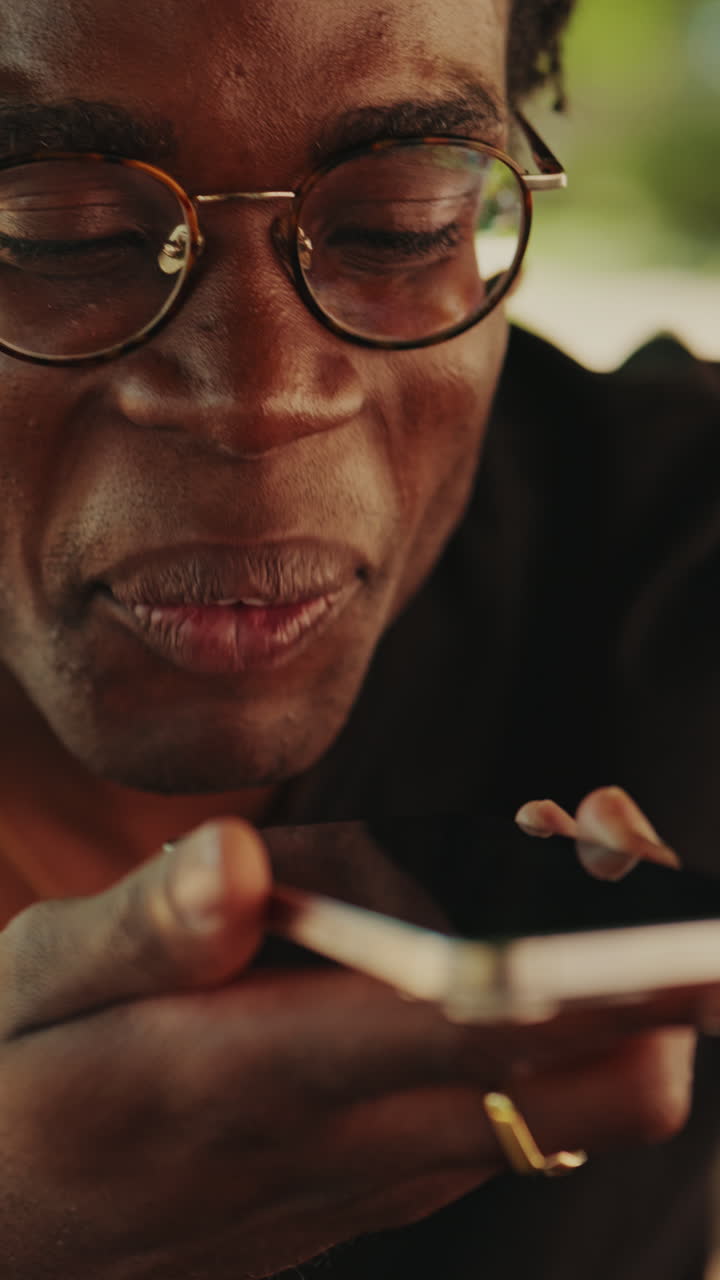 Happy Young African American Man Speaking into Smartphone