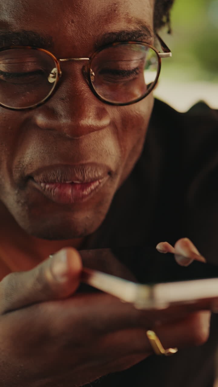 Happy Young African American Man Speaking into Smartphone