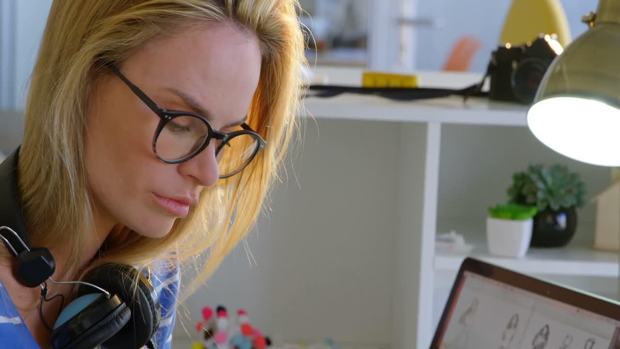 vista lateral de una diseñadora de moda caucásica usando una tableta gráfica en el escritorio en la oficina 4k