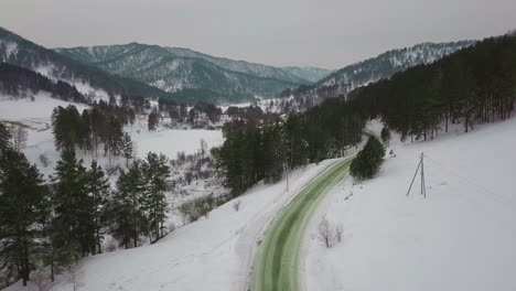 Road-stretches-through-lush-coniferous-forest-on-snowy-slope