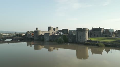king john's castle with mirrored water reflection on river shannon in limerick, ireland. wide zoom-out shot