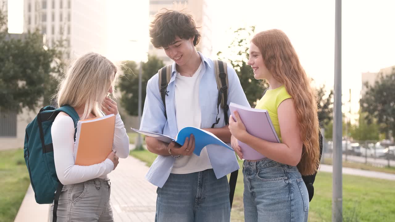 Šťastní mladí studenti diskutují o poznámkách v univerzitním kampusu