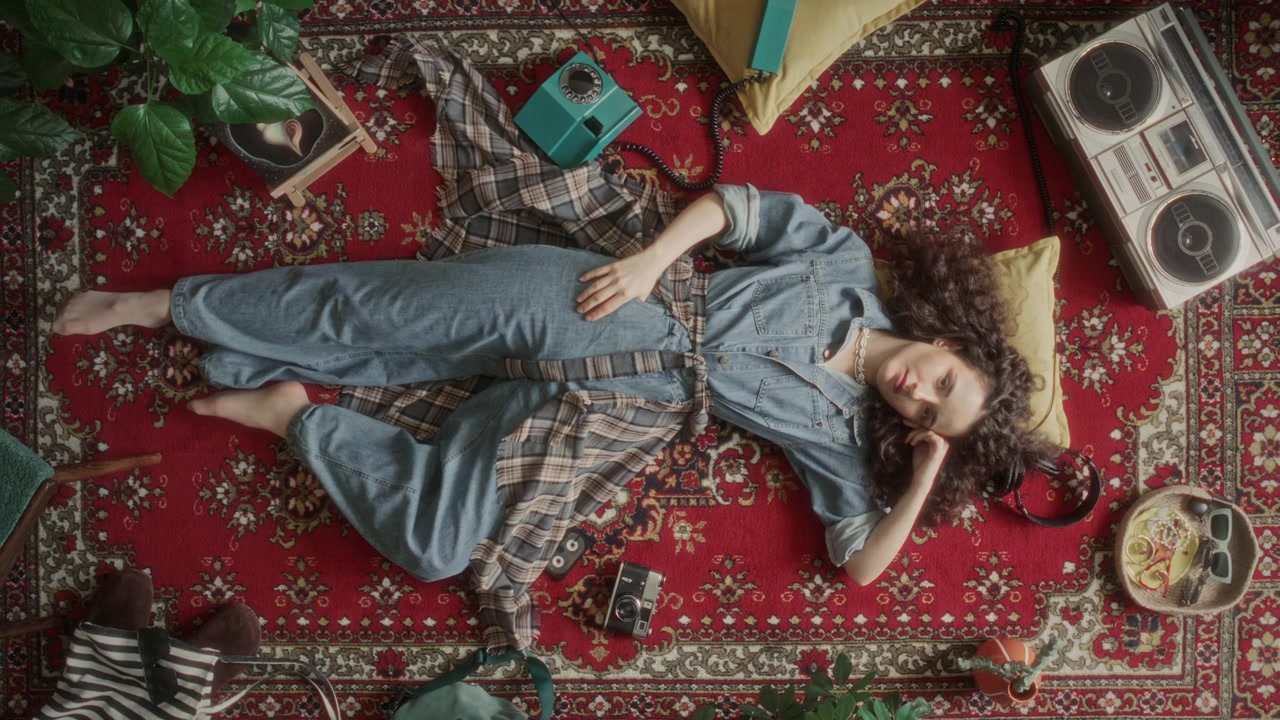 Top Down of Woman Lying on Vintage Rug with Retro Boombox and Rotary Phone
