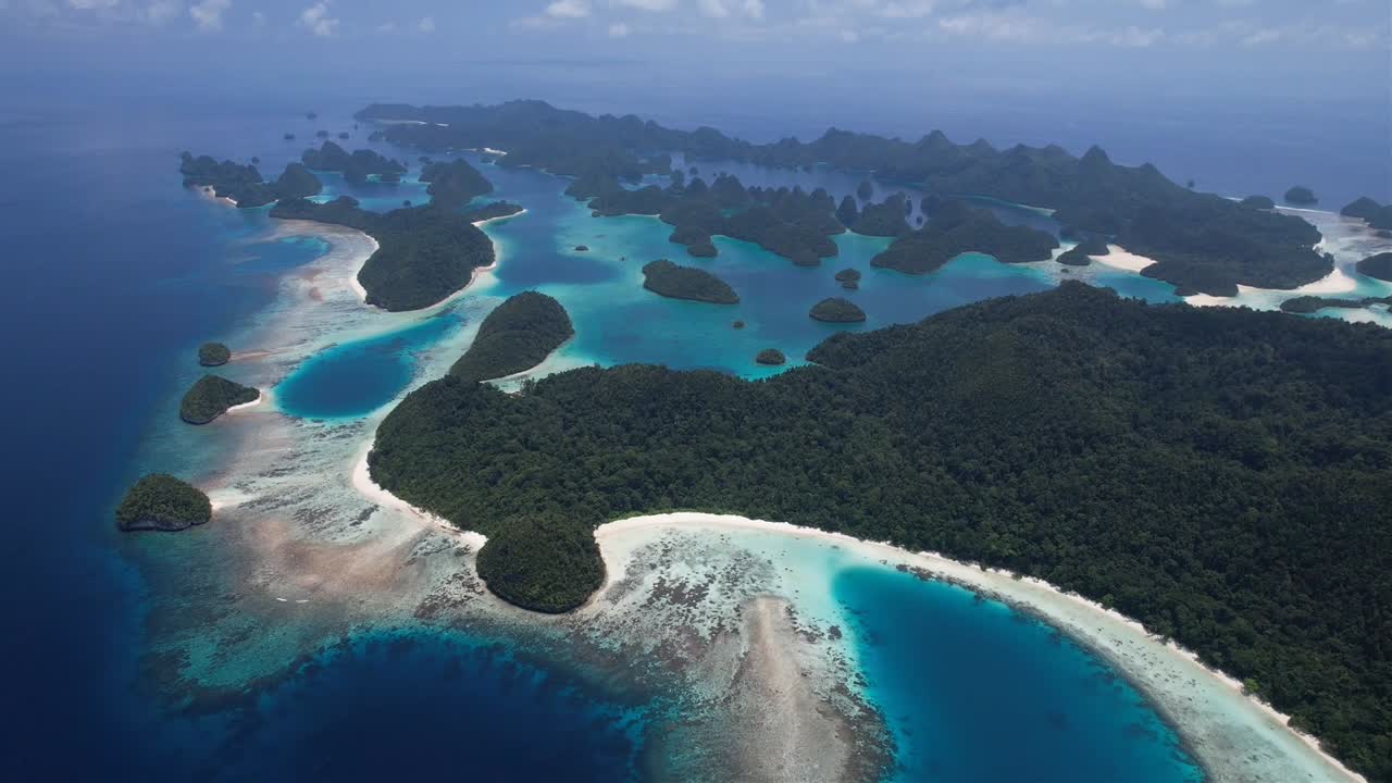Flying backwards, high altitude stunning view on many islands, white sandy beaches, lush green flora, coral reefs in Raja Ampat, Wayag, Indonesia