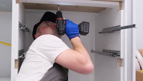 a qualified craftsman in special clothes installs furniture using an electric drill a qualified craftsman in special clothes installs furniture using an electric drill installation of fittings in a new house home renovation concept video