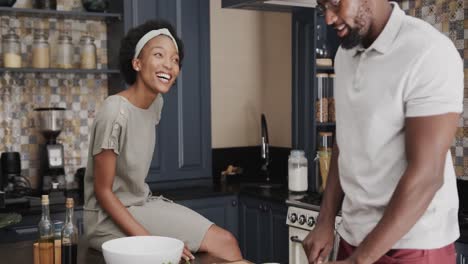 Happy-african-american-couple-talking-and-cooking-together-in-ktichen-in-slow-motion