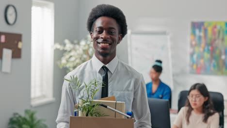 man with afro hair quits corporate job leaves office with things packed in box leaves corporate, checks to make sure he took everything, quits job, retires, happy smiling