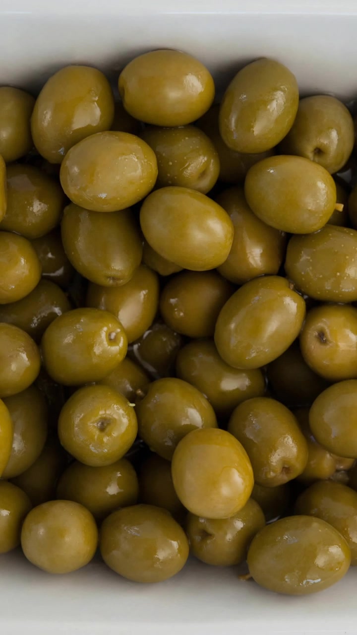 Animazione di olive verdi in ciotola su sfondo bianco
