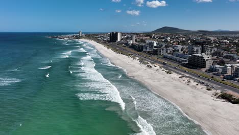 Drohnenflug-über-Die-Küste-Von-Bloubergstrand-Mit-Strandgebäuden-In-Kapstadt,-Südafrika,-An-Sonnigen-Tagen